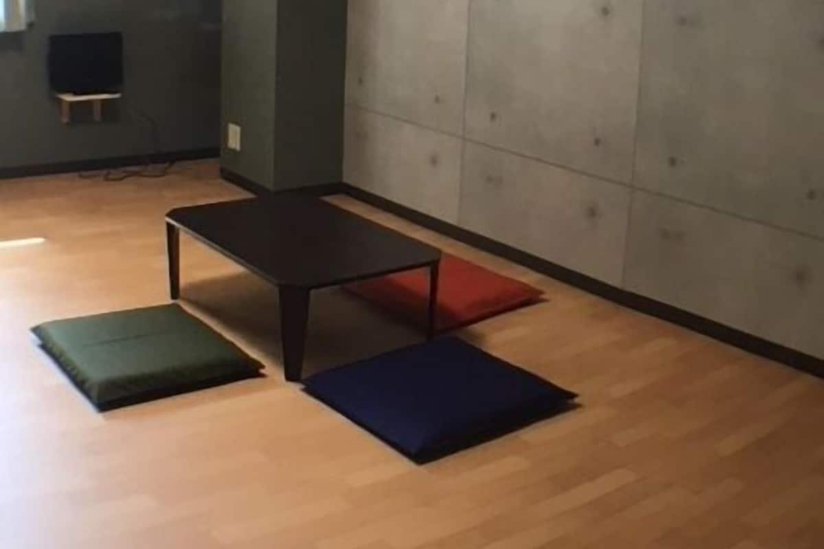 Um quarto com piso de madeira, uma mesa escura e uma parede acolchoada.