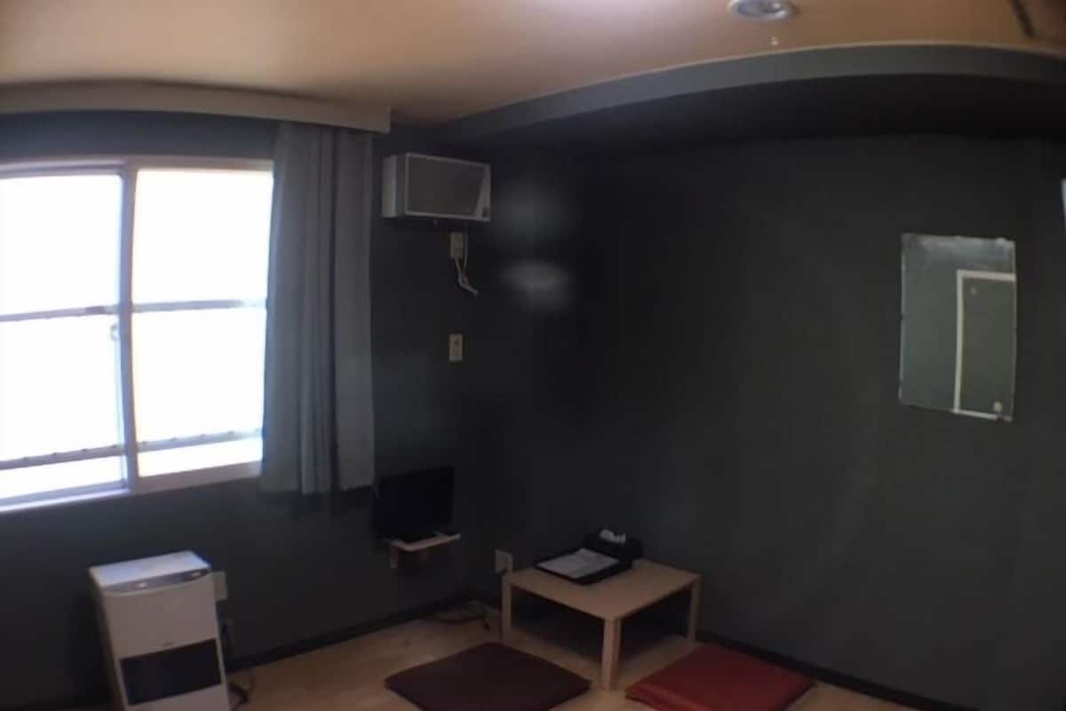 Quarto com janela, escrivaninha, cadeira, mesinha e armário.