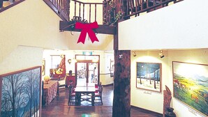 Un hall d’entrée spacieux avec un escalier en bois, un coin repas et des œuvres d’art accrochées aux murs.