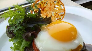 Une assiette avec un œuf au plat, des légumes verts et un objet décoratif.