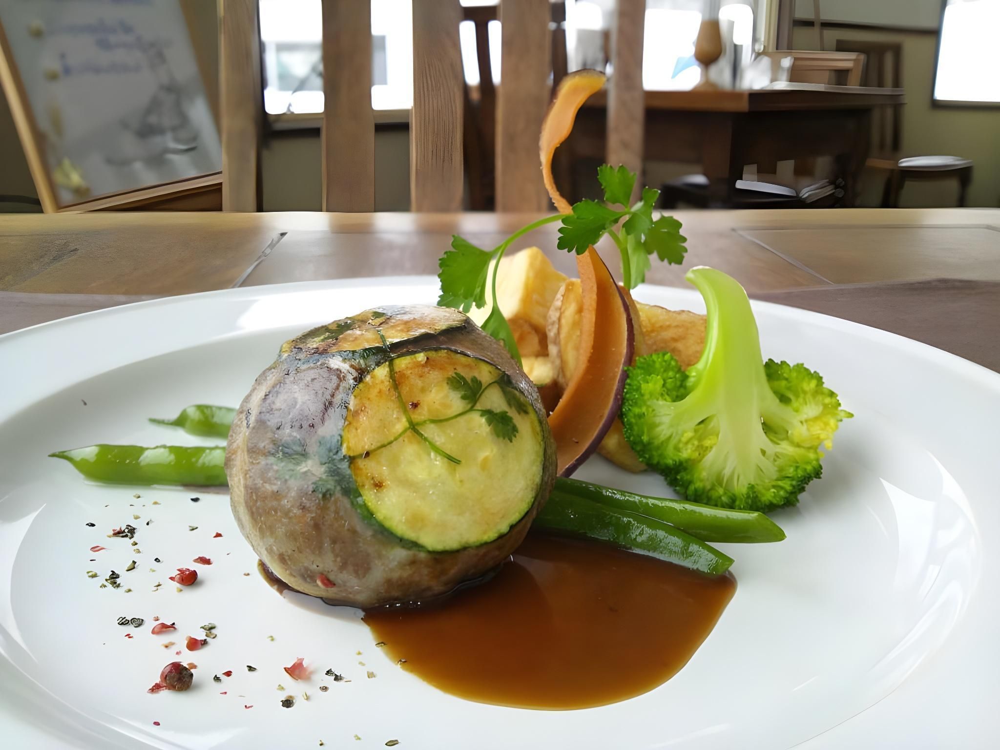 A plate with a rolled meat dish, broccoli, and a sauce.