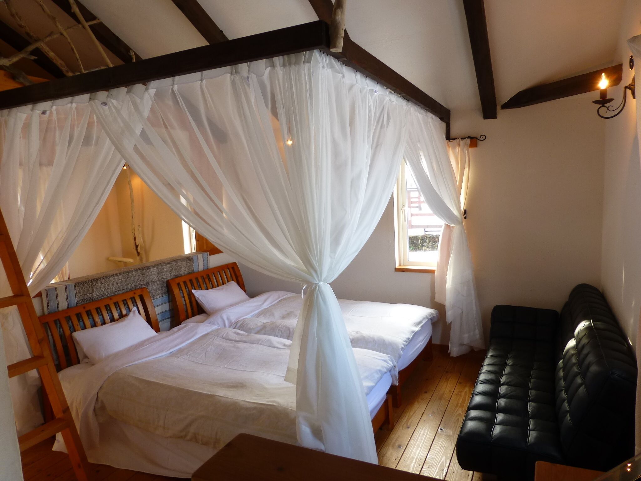 Een kamer met een bed, een bankje en een raam.