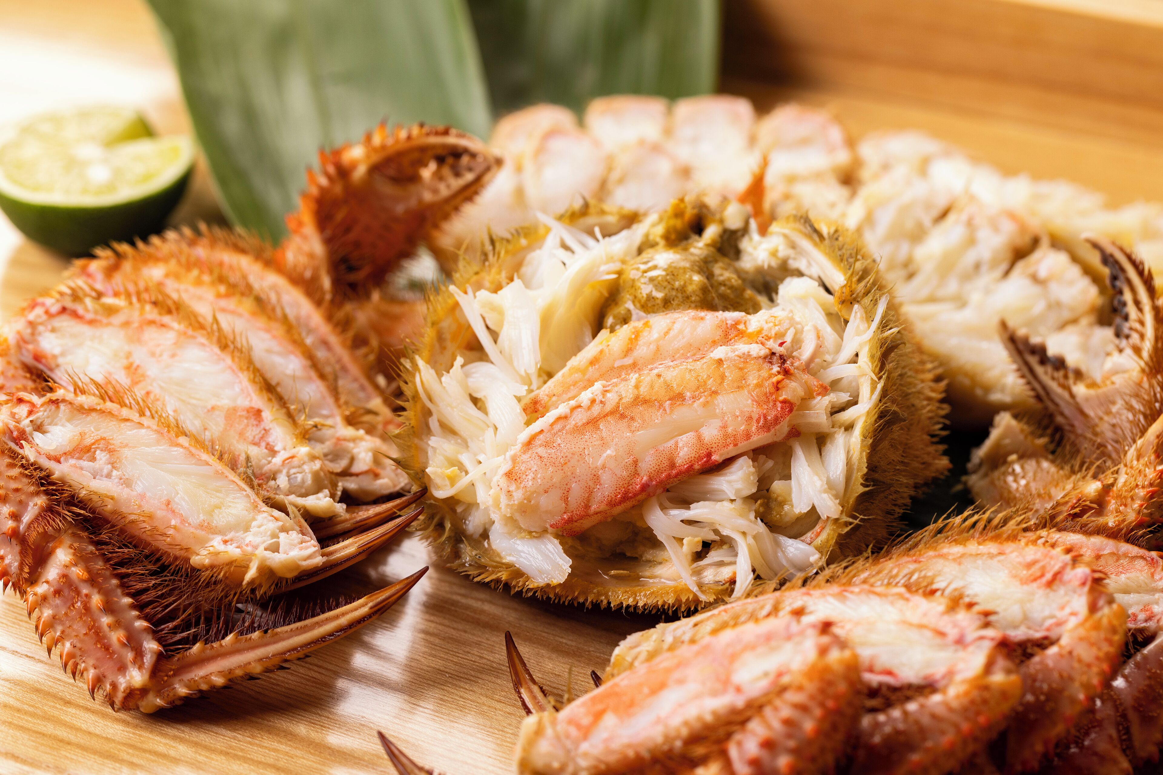 A wooden cutting board with crab legs and a lime half.