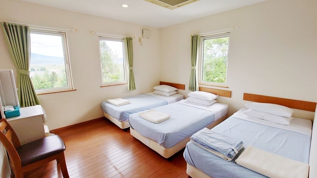 A room with three beds, a desk, and a chair.