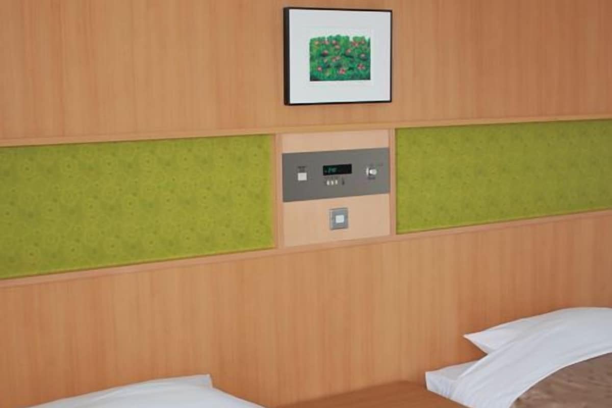 Habitación de hotel con dos camas, un panel de control y un cuadro en la pared.