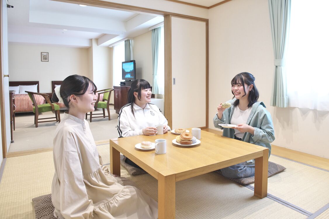 A room with tatami mats, a wooden table, and a television in the background.