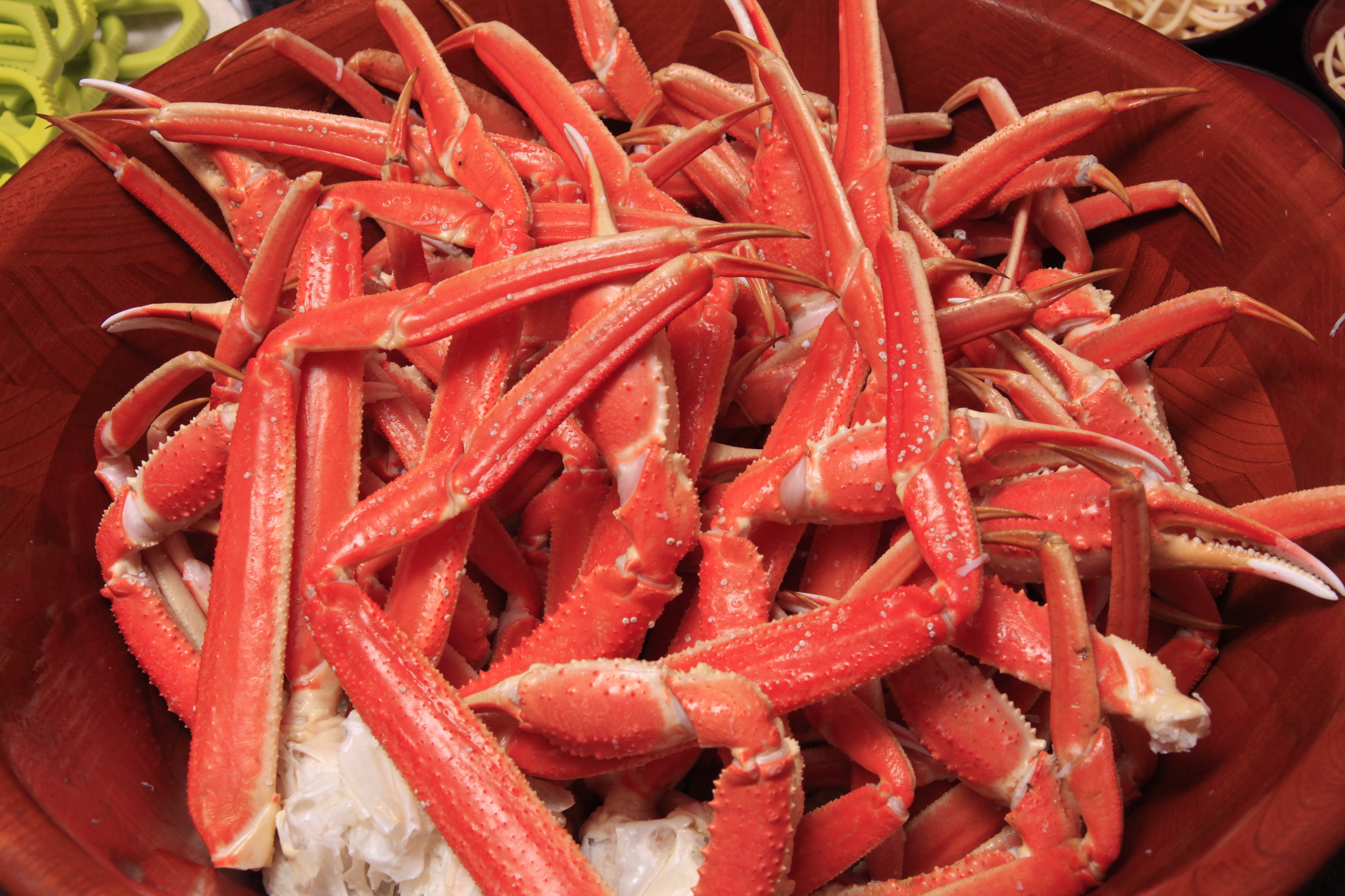 A wooden bowl filled with red crab legs.