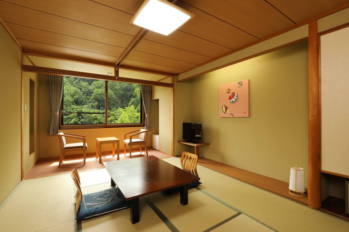 Ett traditionellt japanskt rum med tatamimattor på golvet, ett lågt bord och fyra stolar.
