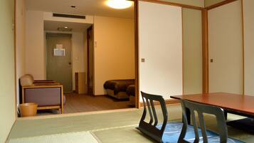 Una habitación japonesa tradicional con suelo de tatami, una mesa baja y un sofá.
