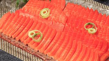 Un plato de vidrio con rebanadas de salmón ordenadas, adornadas con cebollines.