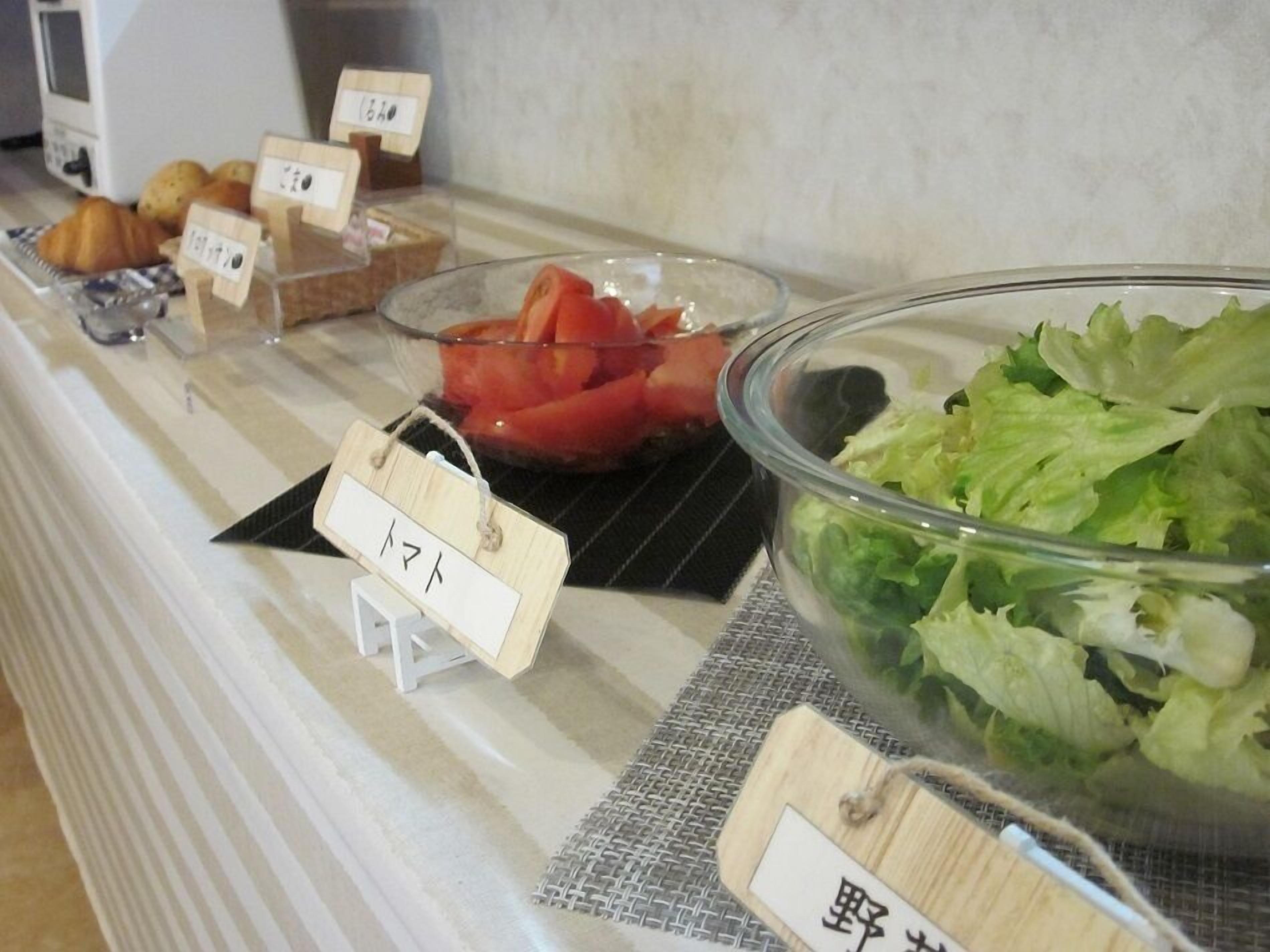 A buffet counter with labeled food items including bread, tomatoes, and lettuce.
