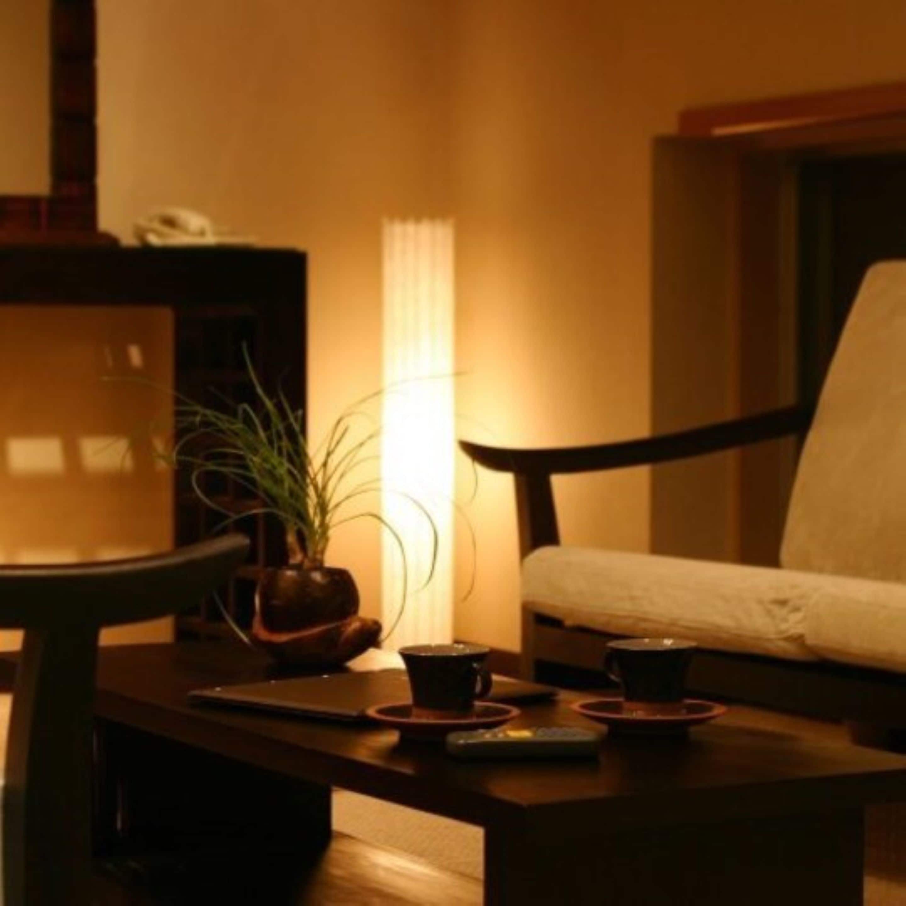 Une pièce chaleureuse avec une table en bois, une chaise, une plante en pot et une lampe.