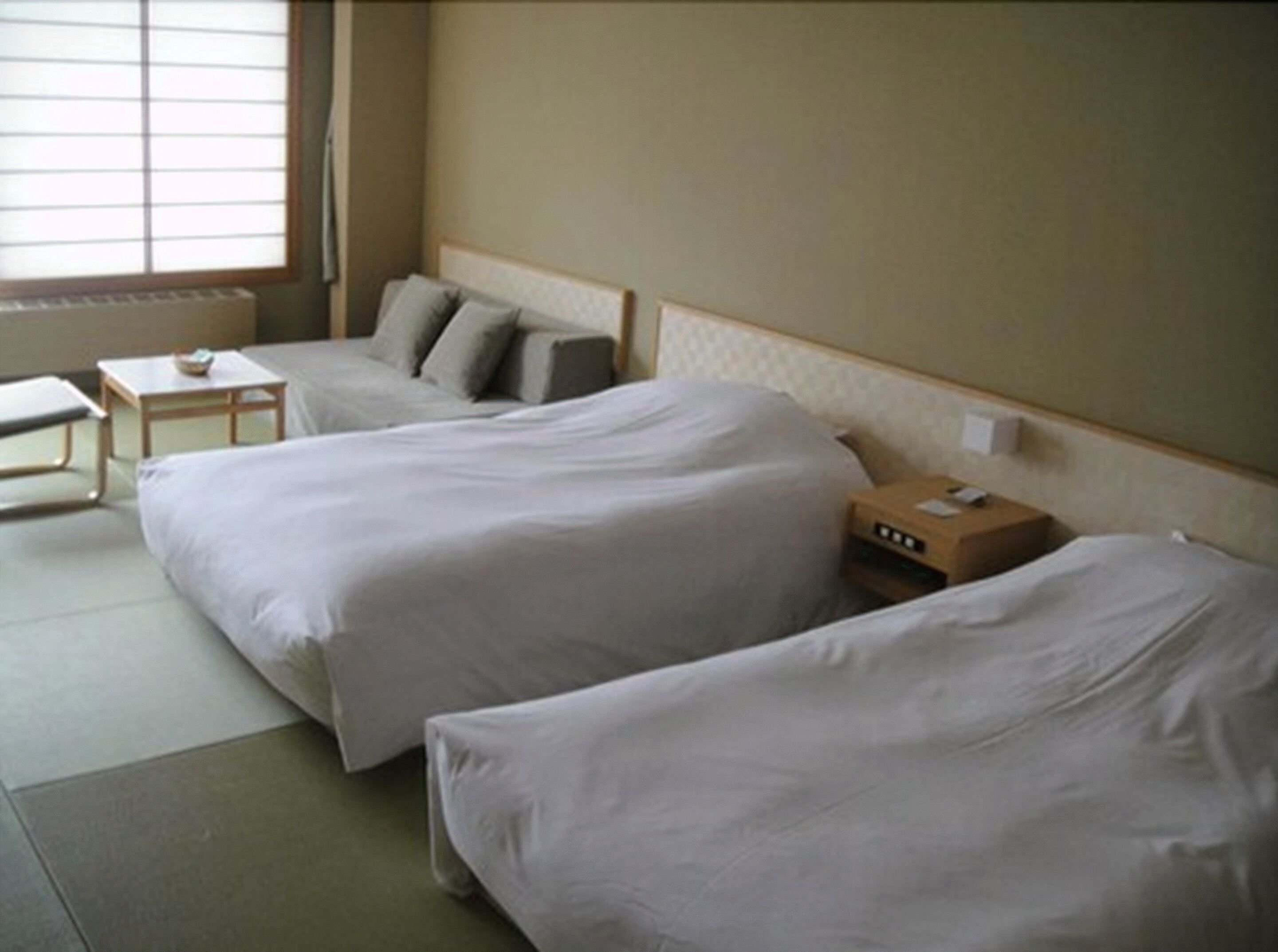 Una habitación de hotel con dos camas, una mesita pequeña y una mesita de noche con una lámpara.