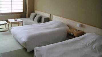 Una habitación de hotel con dos camas, una mesita pequeña y una mesita de noche con una lámpara.