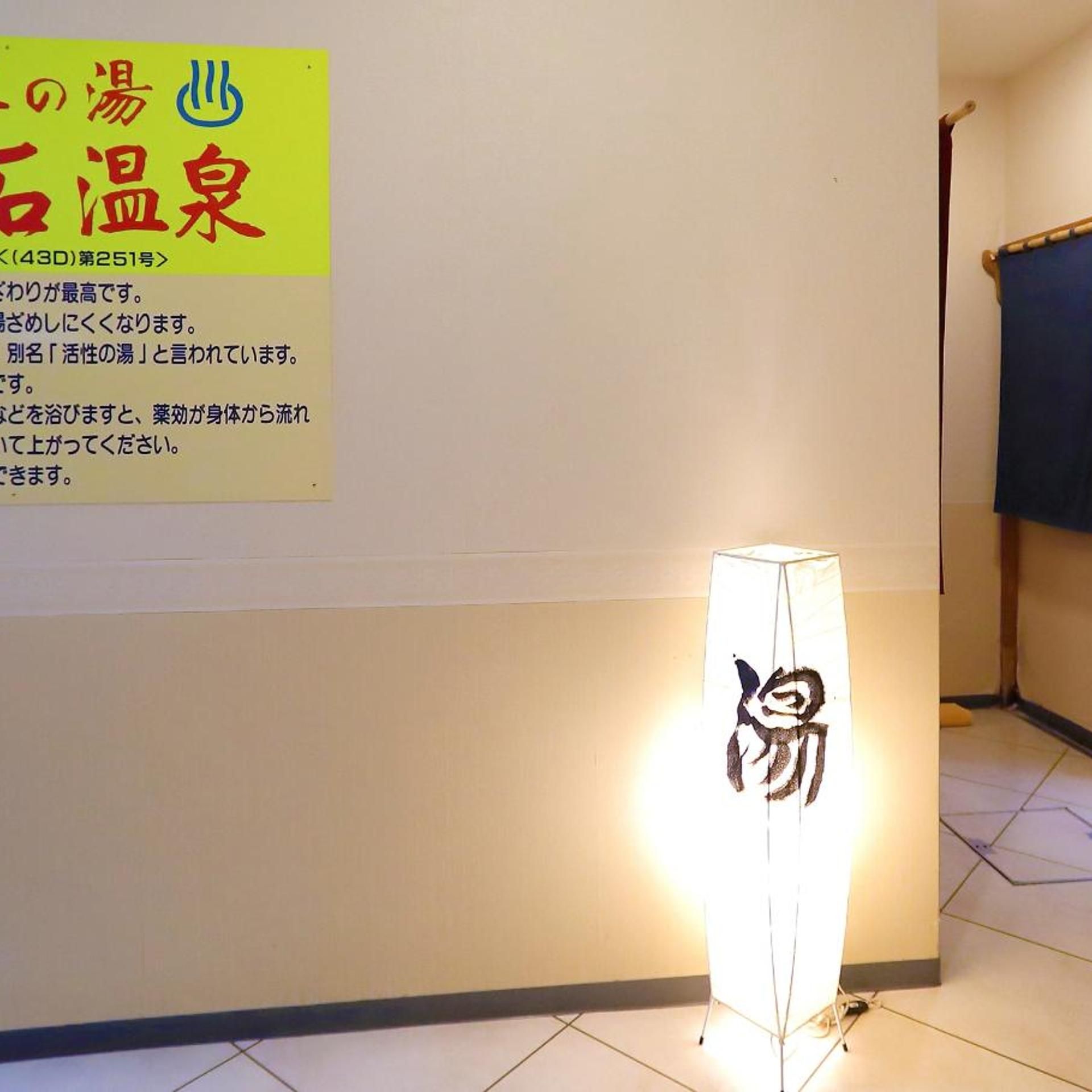 A room with a standing lamp featuring a panda design, a wall-mounted sign with Japanese text, and a blue curtain.