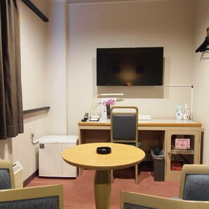 A hotel room with a television, a desk with a chair, a small refrigerator, and a round table. - Hotel Sato (Shinhidaka)