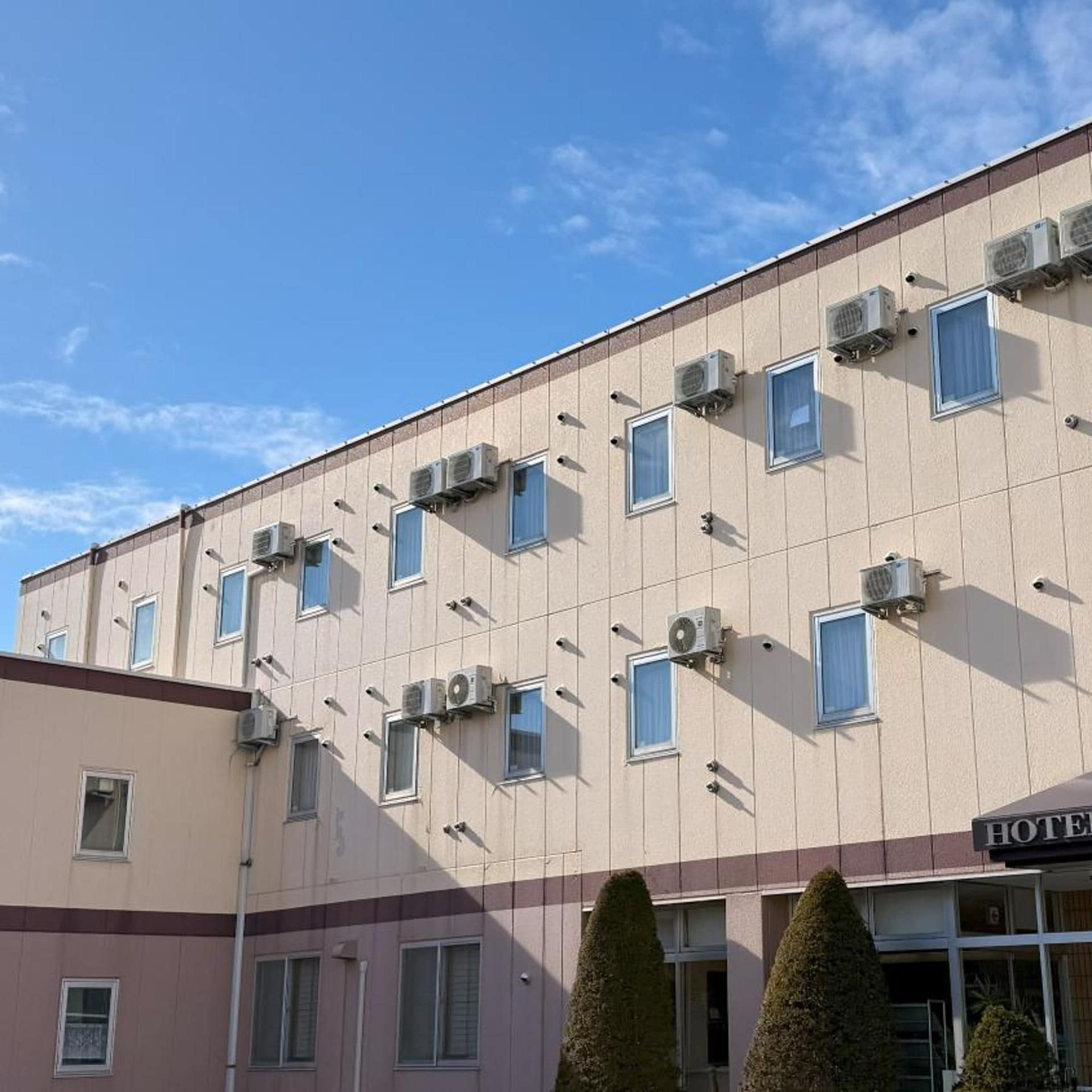 A multi-story hotel building with air conditioning units attached to the exterior walls and a sign indicating it is a hotel.