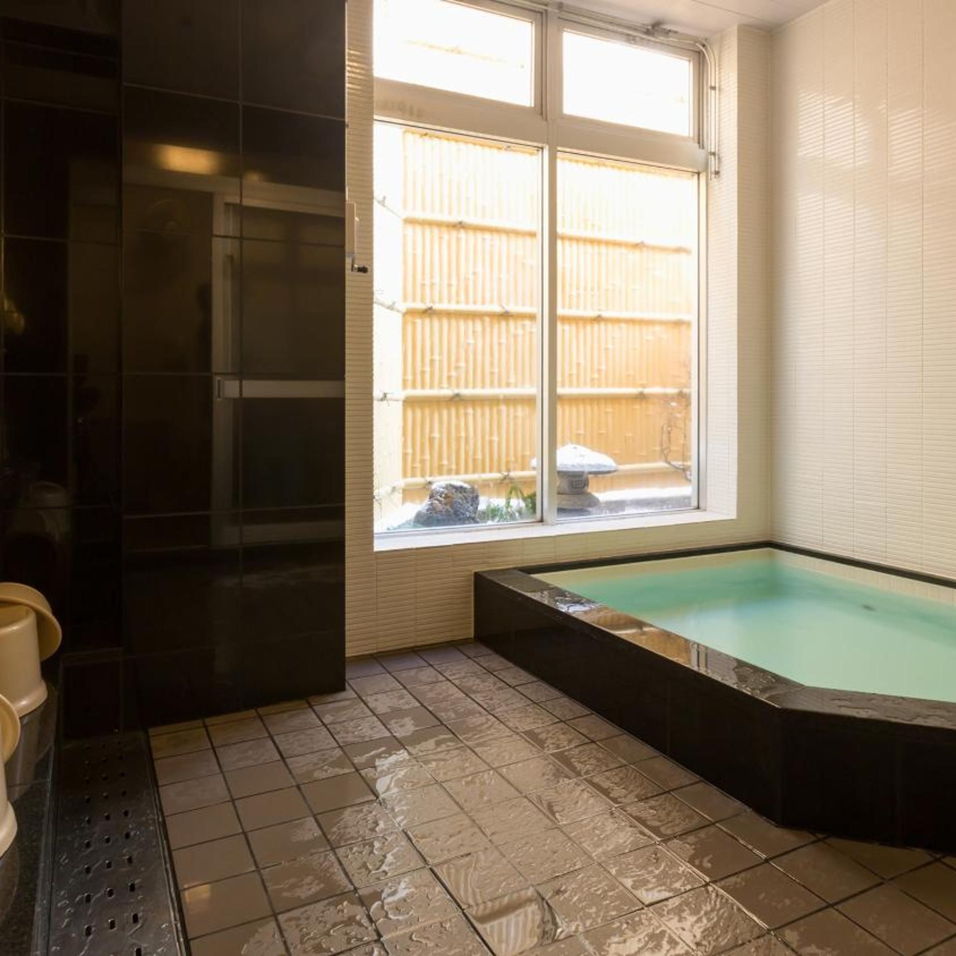 Une salle de bain avec une baignoire, une fenêtre et un sol carrelé.