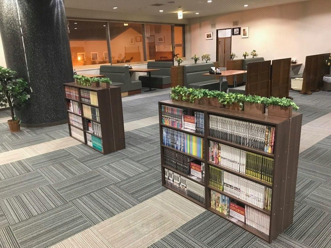 A library area with bookshelves, seating, and a large pillar.