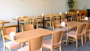 A conference room with multiple tables and chairs, arranged in rows.
