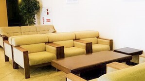 A sectional sofa with wooden armrests and a matching coffee table in a room with a tiled floor.
