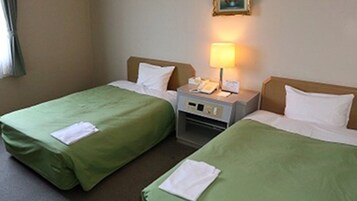 A hotel room with two single beds, a bedside table with a lamp, and a small nightstand with a phone.