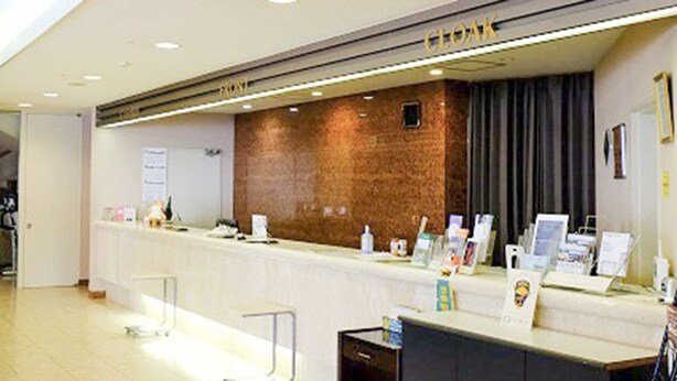 A reception desk with a brick wall backdrop, a counter with informational brochures, and a door to the left.