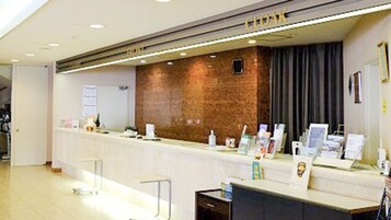 Un mostrador de recepción con un fondo de pared de ladrillo, folletos informativos sobre la barra y una puerta a la izquierda.
