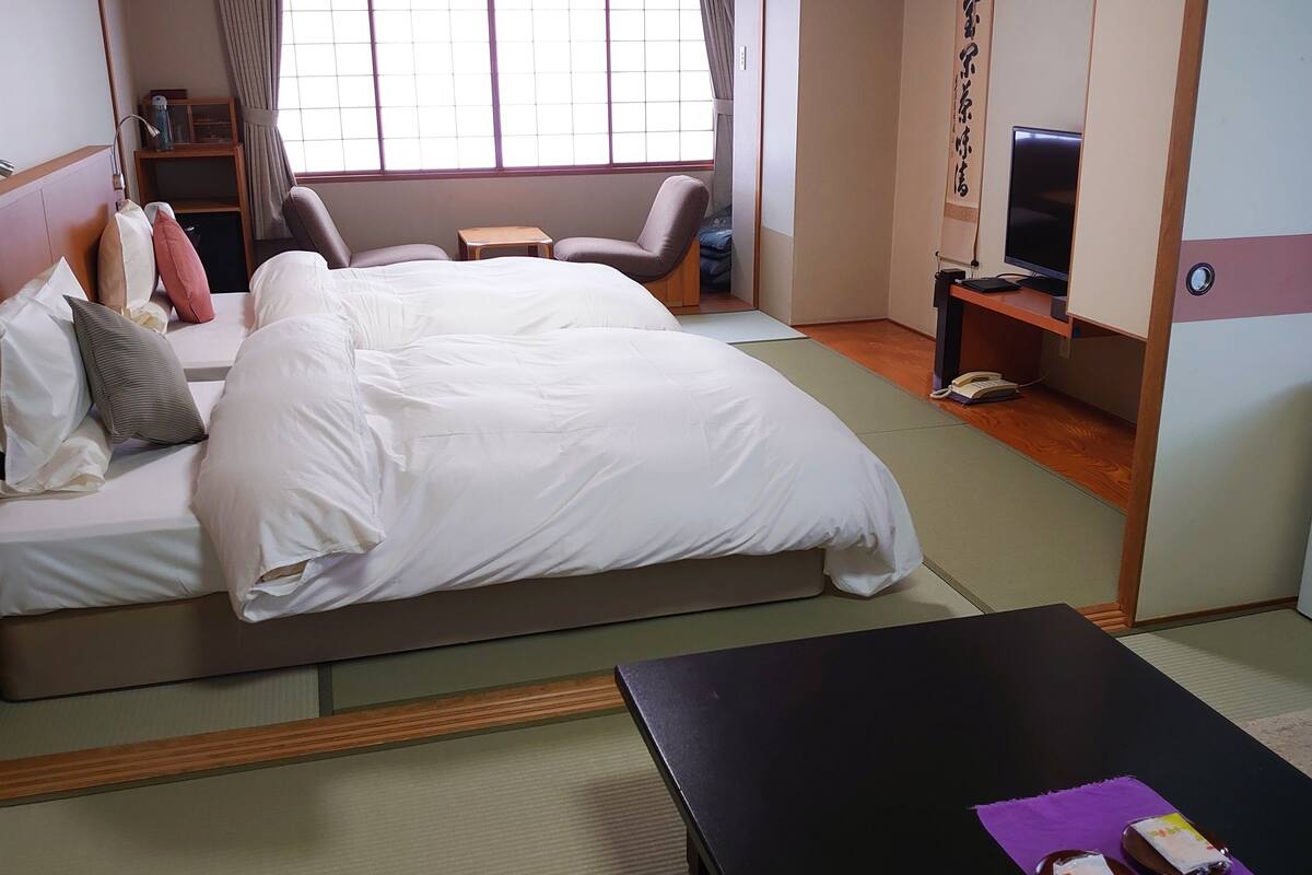 A hotel room with a bed, a desk, a TV, a wardrobe, and a window.