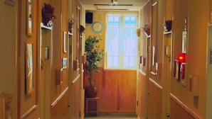 Un couloir avec des portes en bois, une plante en pot et une horloge au mur.