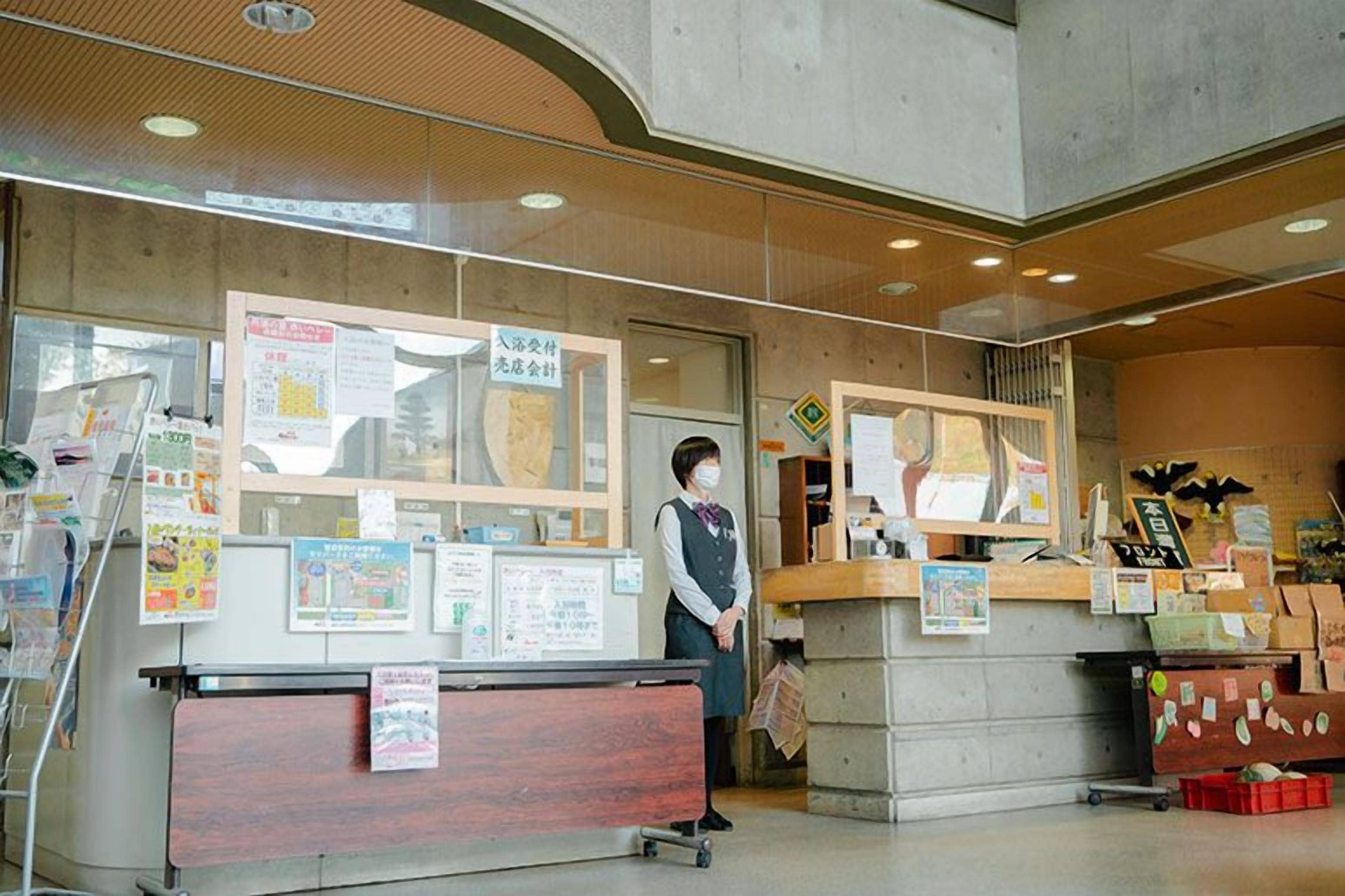 Una recepción con carteles informativos, un mostrador con diversos artículos y una persona detrás.