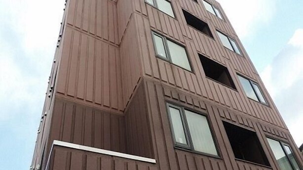 Un edificio de varios pisos con un diseño angular distintivo, grandes ventanales y fachada metálica.