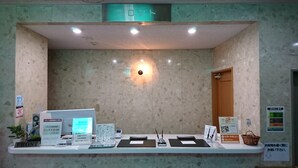 Un mostrador de recepción con una computadora, una impresora y un cartel que indica la disponibilidad de Wi-Fi.