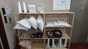 Una habitación con estanterías que exhiben almohadas, un extintor y un plano del piso en la pared.