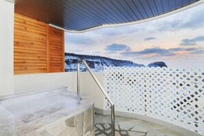 Zona de spa con un banco de piedra, pared de madera y vista a un paisaje nevado.