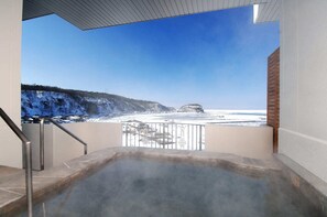 A hot tub with a view of a snowy landscape and a clear blue sky.