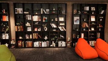A room with a large bookshelf filled with books and decorative items, two orange bean bag chairs, and a wooden floor.