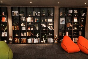 A room with a large bookshelf filled with books and decorative items, two orange bean bag chairs, and a wooden floor. - Rembrandt Resort Shiretoko (Shari)