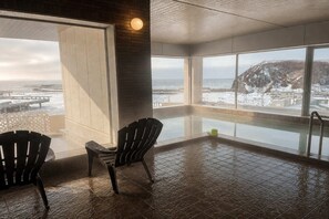 A room with a large window overlooking a snowy landscape and a pool area with two chairs. - Rembrandt Resort Shiretoko (Shari)