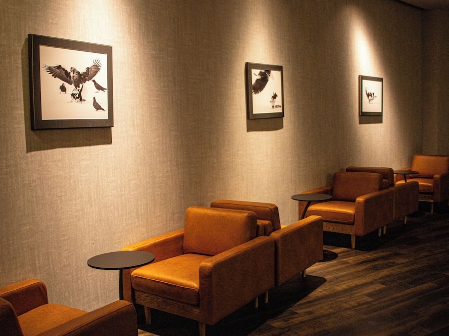 A hotel lobby with leather armchairs, small round tables, and framed wall art.