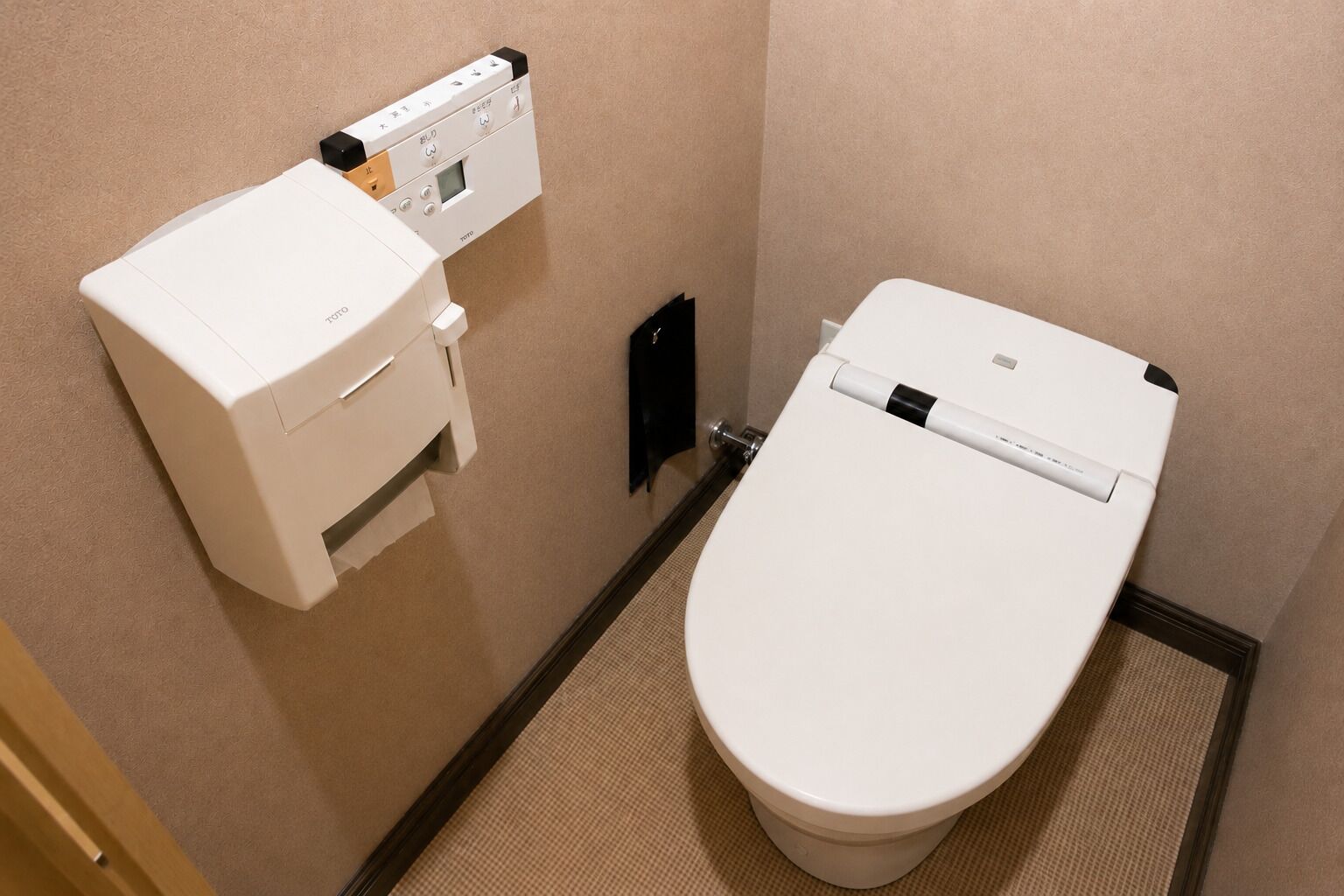A toilet with a control panel and a bidet attachment.