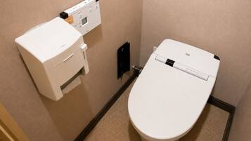 A toilet with a control panel and a bidet attachment.