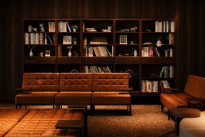 A library with a brown leather sofa, multiple bookshelves, and a carpeted floor. - Rembrandt Resort Shiretoko (Shari)