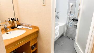 A bathroom with a sink, mirror, toiletries, and a shower.