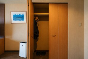 A hotel room with a wooden wardrobe, a framed picture on the wall, and a small trash bin. - Rembrandt Resort Shiretoko (Shari)