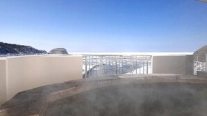 En balkon med udsigt over et sneklædt landskab og en klar blå himmel.