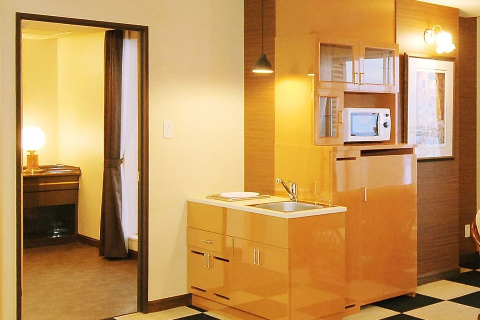 A compact kitchen with a microwave, sink, and cabinets.