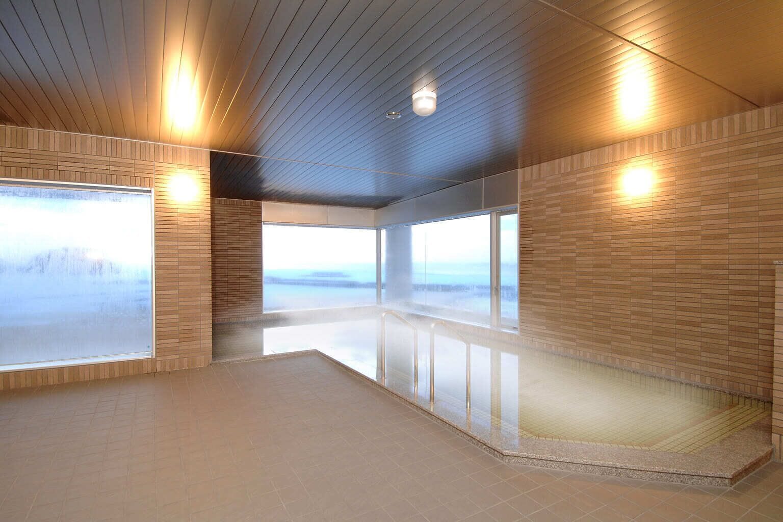 A spacious indoor area with a high ceiling, large windows, and a reflective floor.