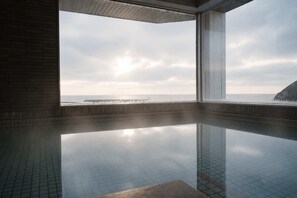 Piscina interior moderna con vista despejada al mar y un muelle distante.