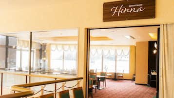A restaurant interior with a sign reading 'Hinna,' a glass partition, and a carpeted floor.